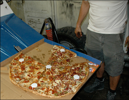 A chorizo pizza, the size of the hood of a Baja 1000 pre-runner, delivered by motorcycle in Tijuana